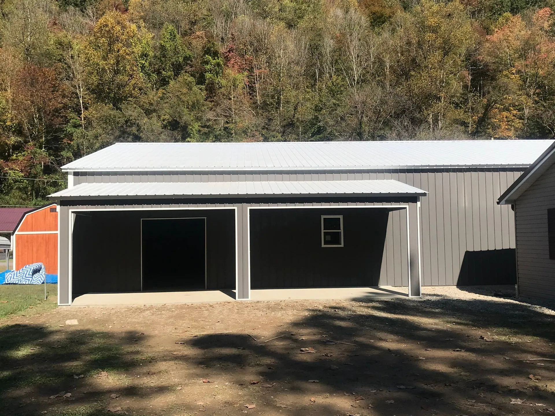 A large barn with a white roof is sitting next to a house.