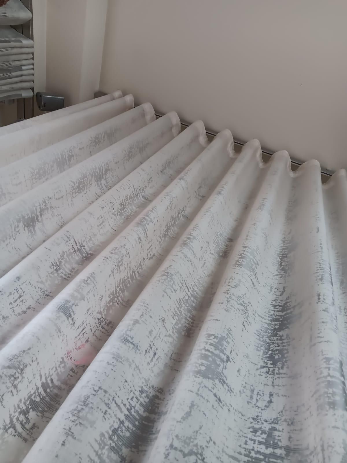 Un primo piano di una fila di tende bianche in una stanza.