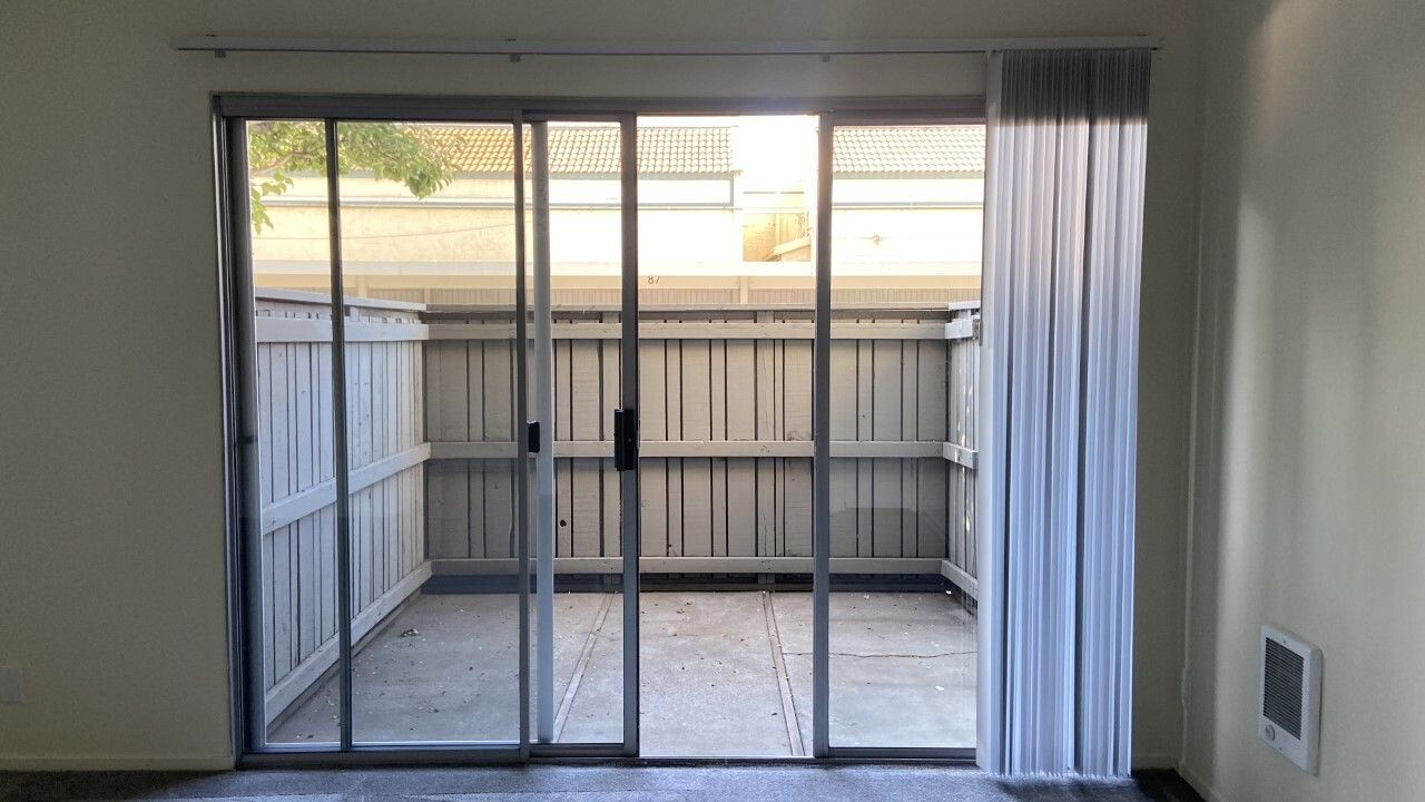 An empty room with a sliding glass door leading to a patio.