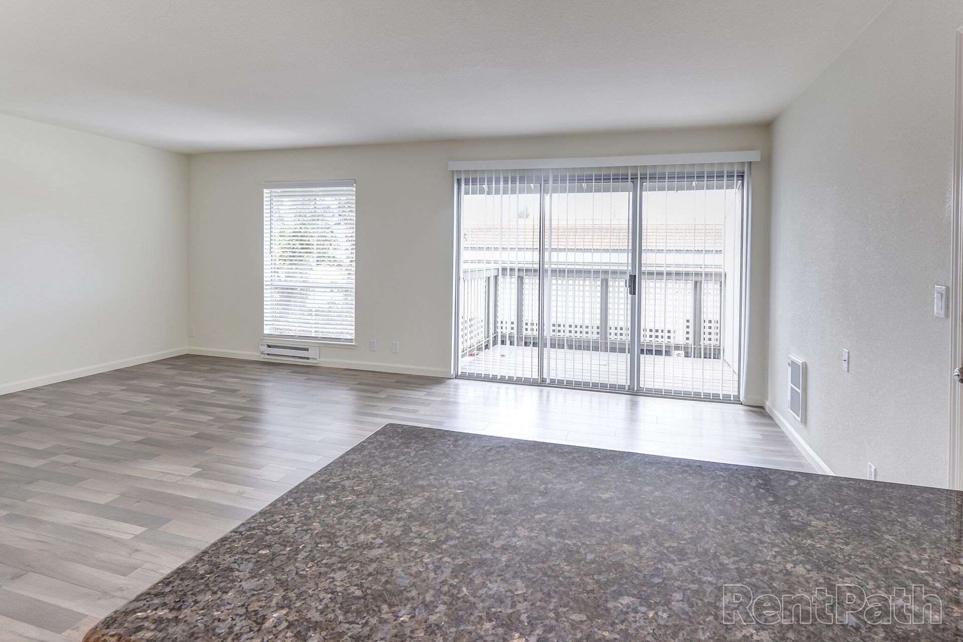 An empty living room with a rug and sliding glass doors leading to a balcony.