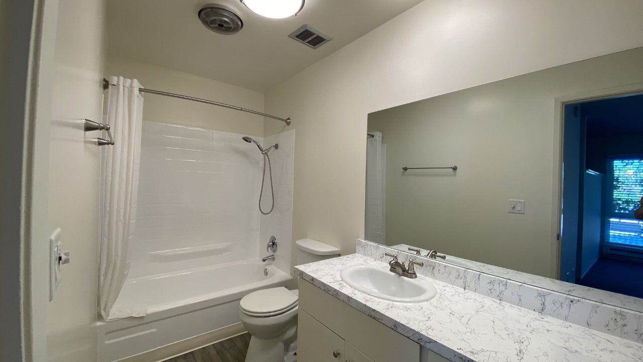 A bathroom with a tub , toilet , sink and mirror.
