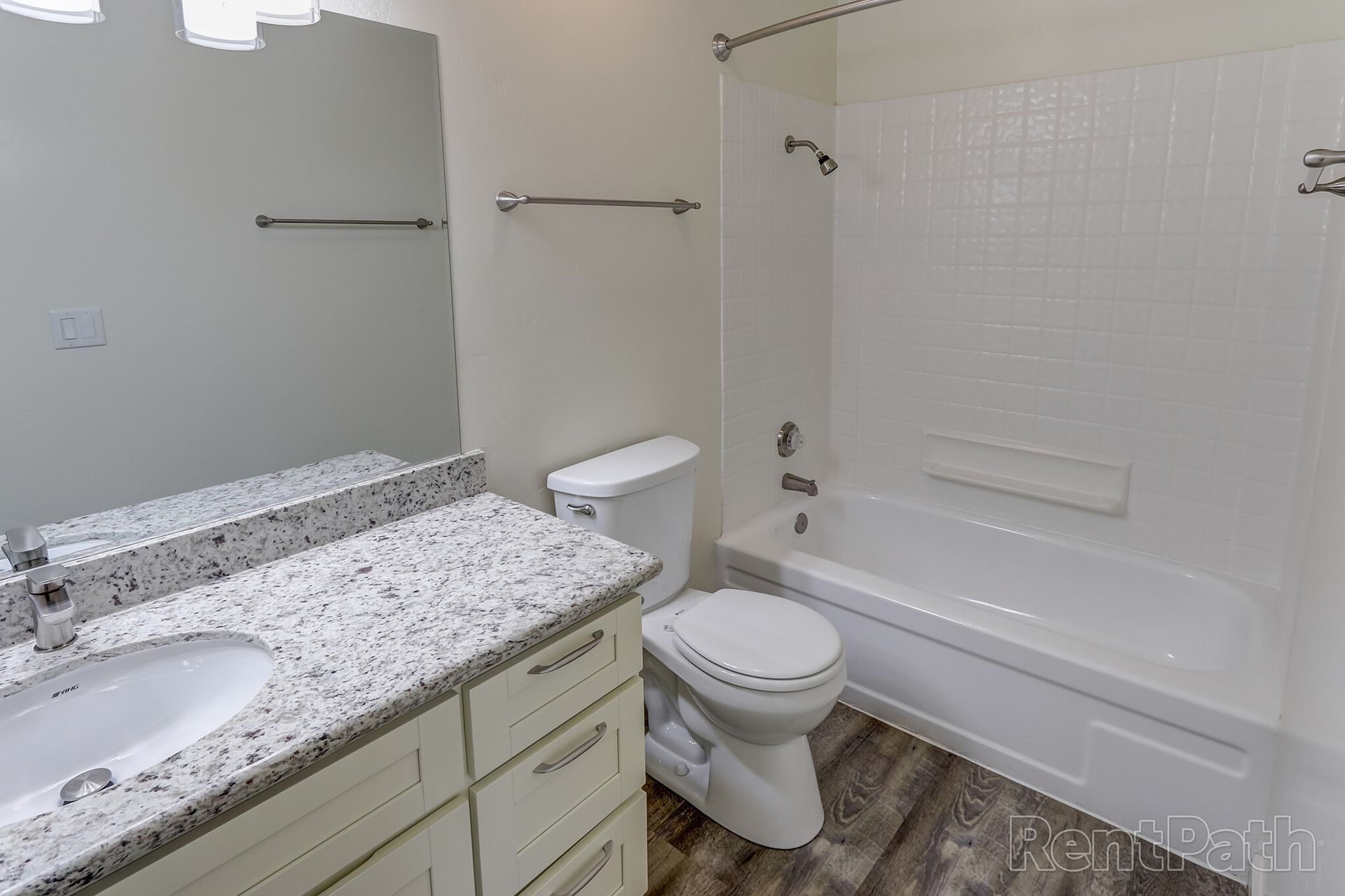 A bathroom with a toilet , sink , bathtub and mirror.