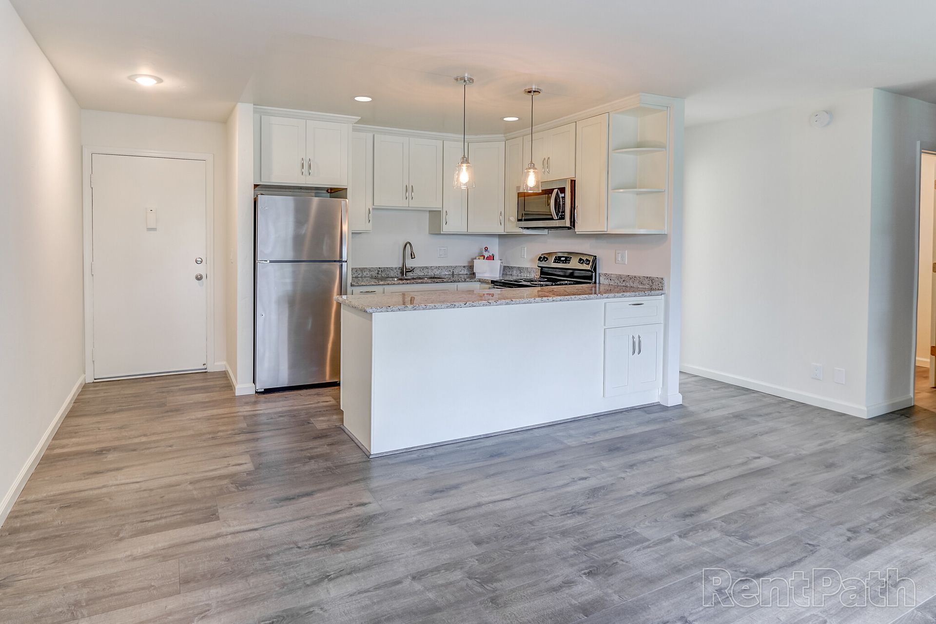 A kitchen with white cabinets , stainless steel appliances , and a large island.