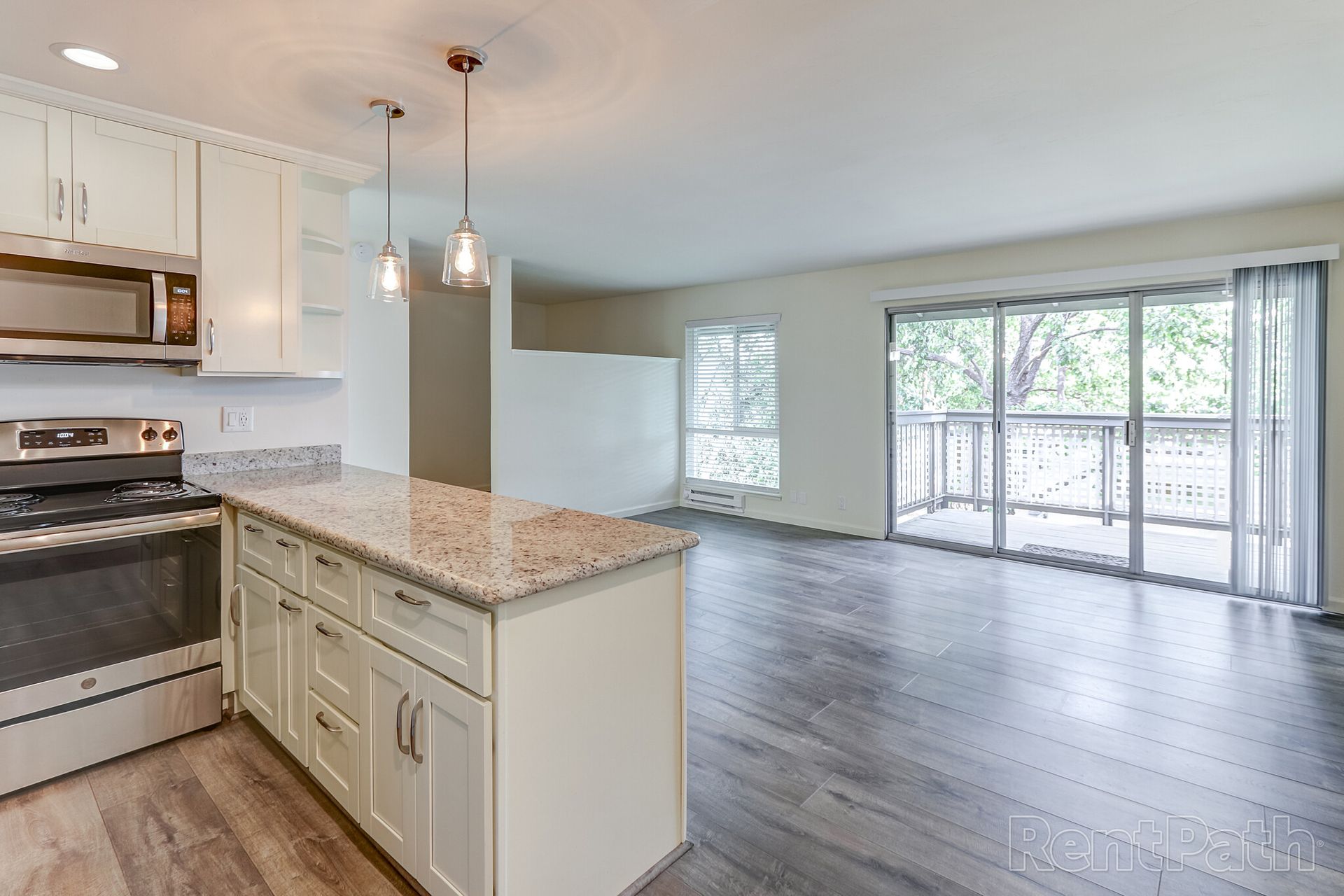 A kitchen with white cabinets , granite counter tops , stainless steel appliances and a large island.