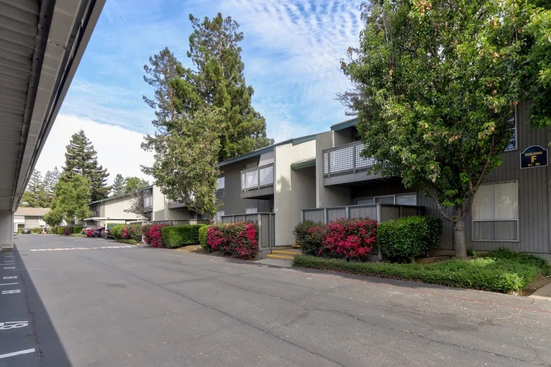 A row of apartment buildings with a parking lot in front of them.