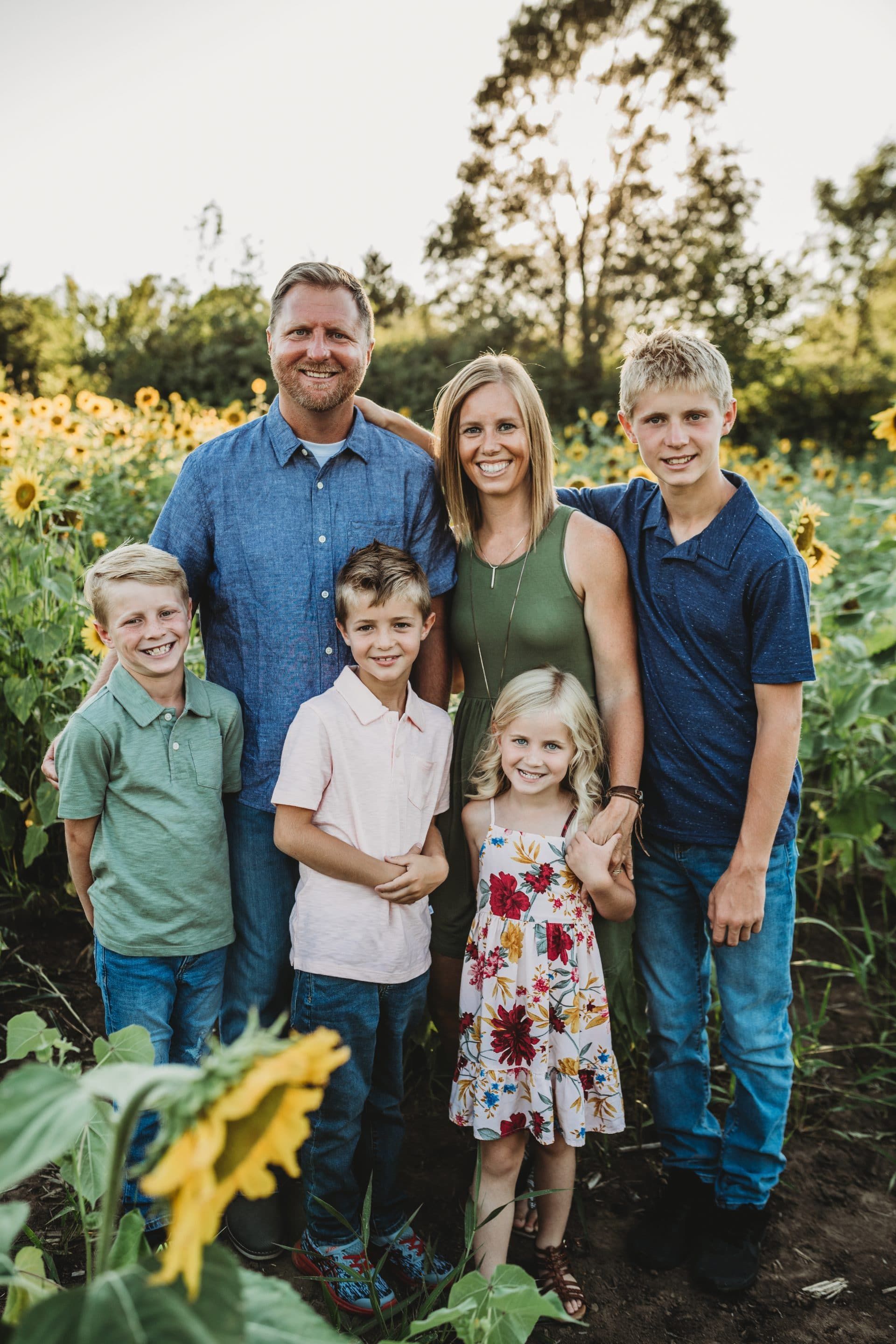 A family is posing for a picture in a field of sunflowers.