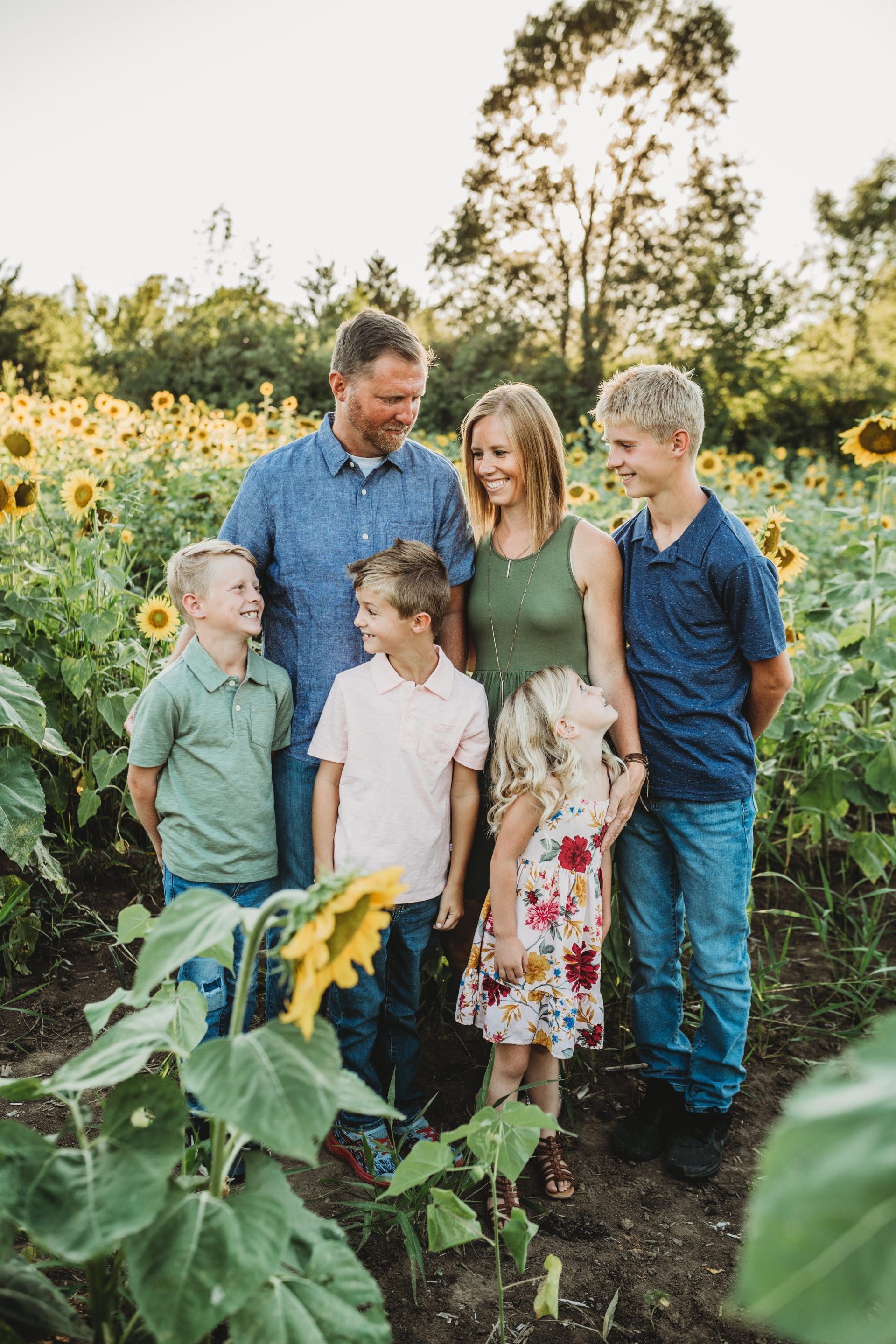 A family is standing in a field of sunflowers.