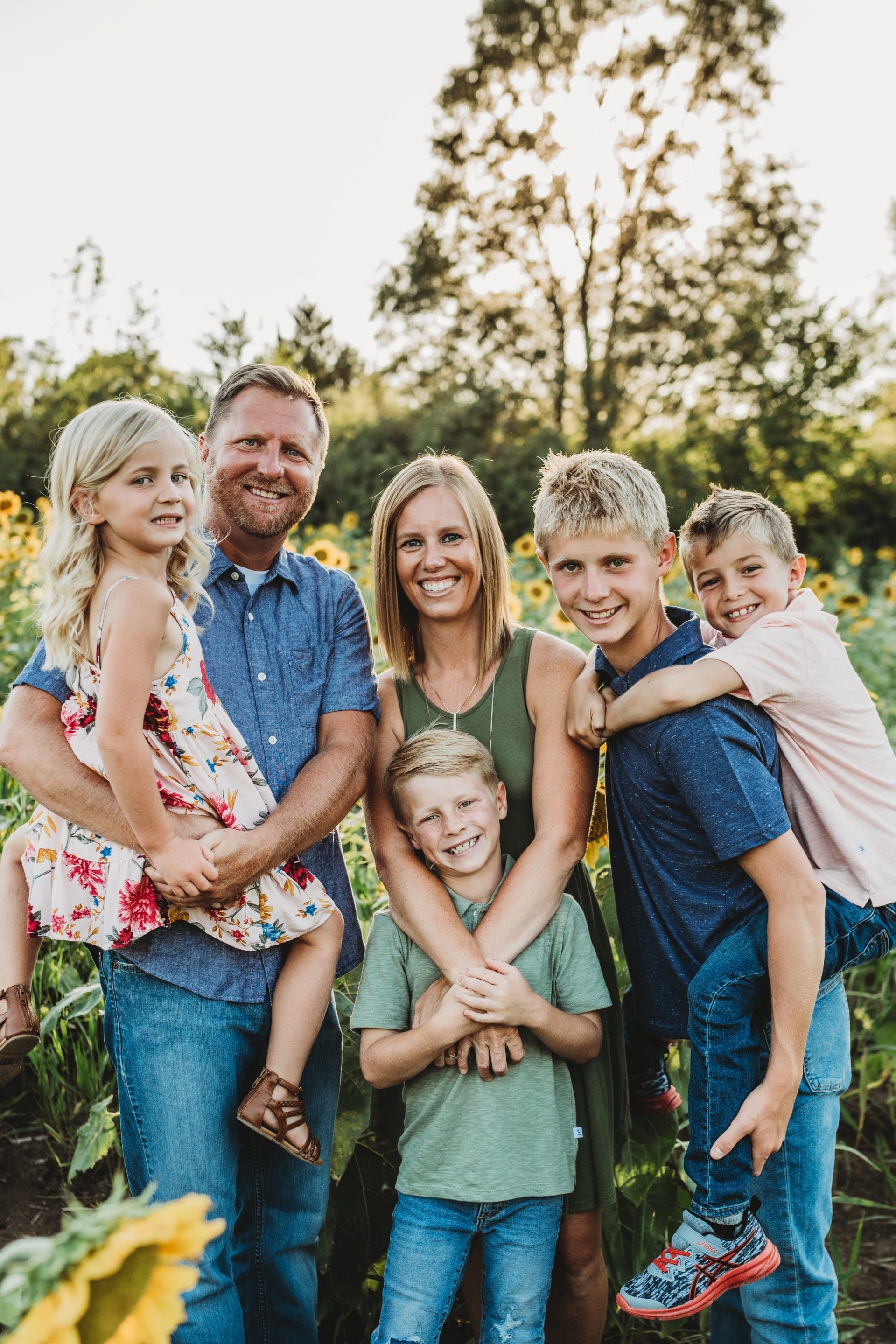 A family is posing for a picture in a field of sunflowers.