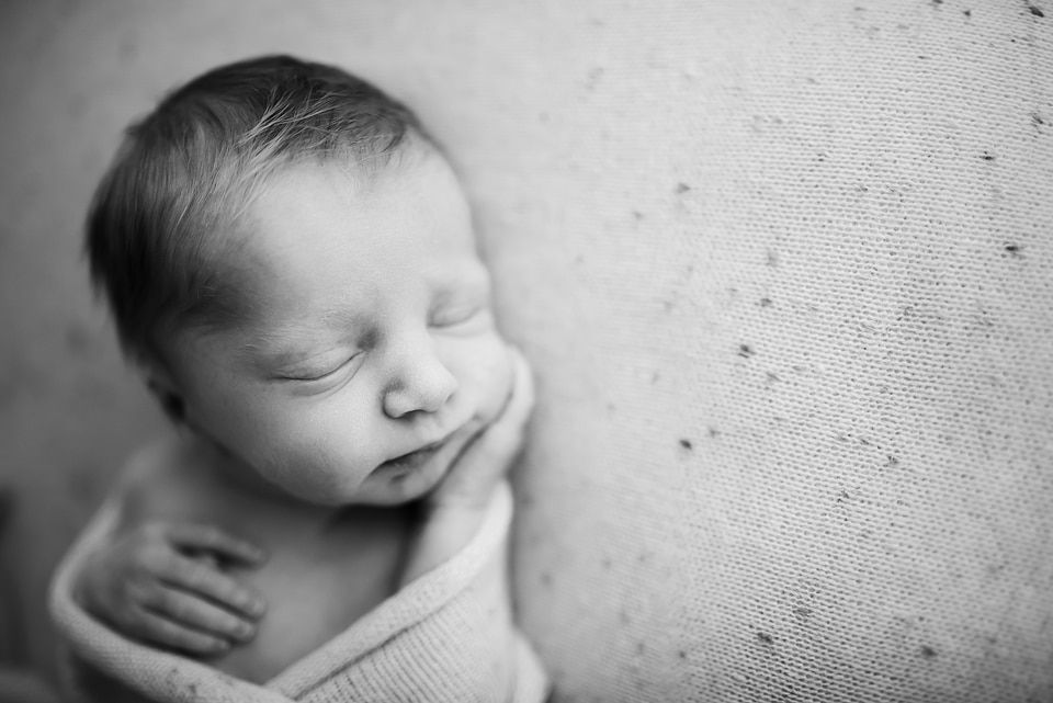 A black and white photo of a newborn baby wrapped in a blanket.