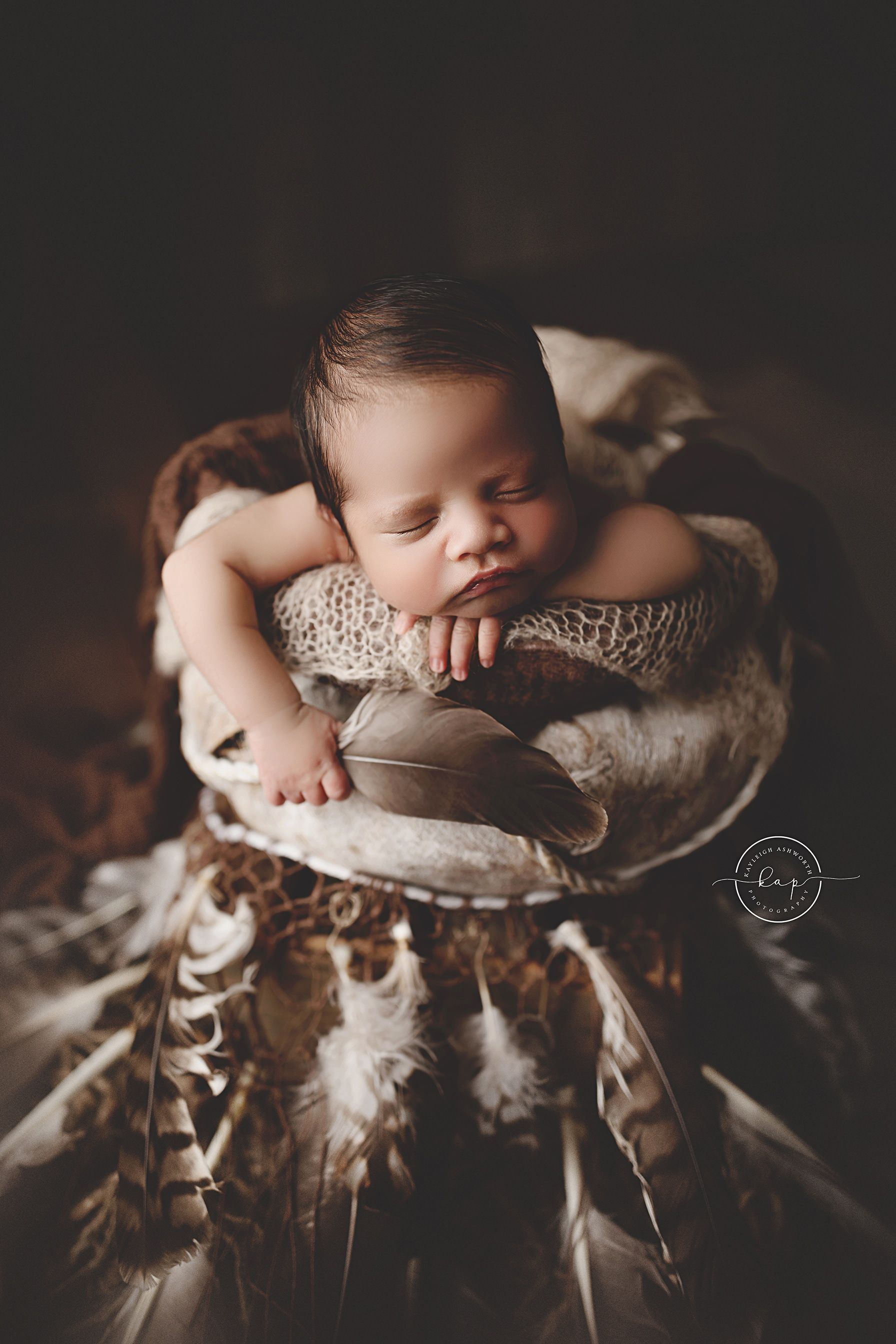 A newborn baby is sleeping in a dream catcher.