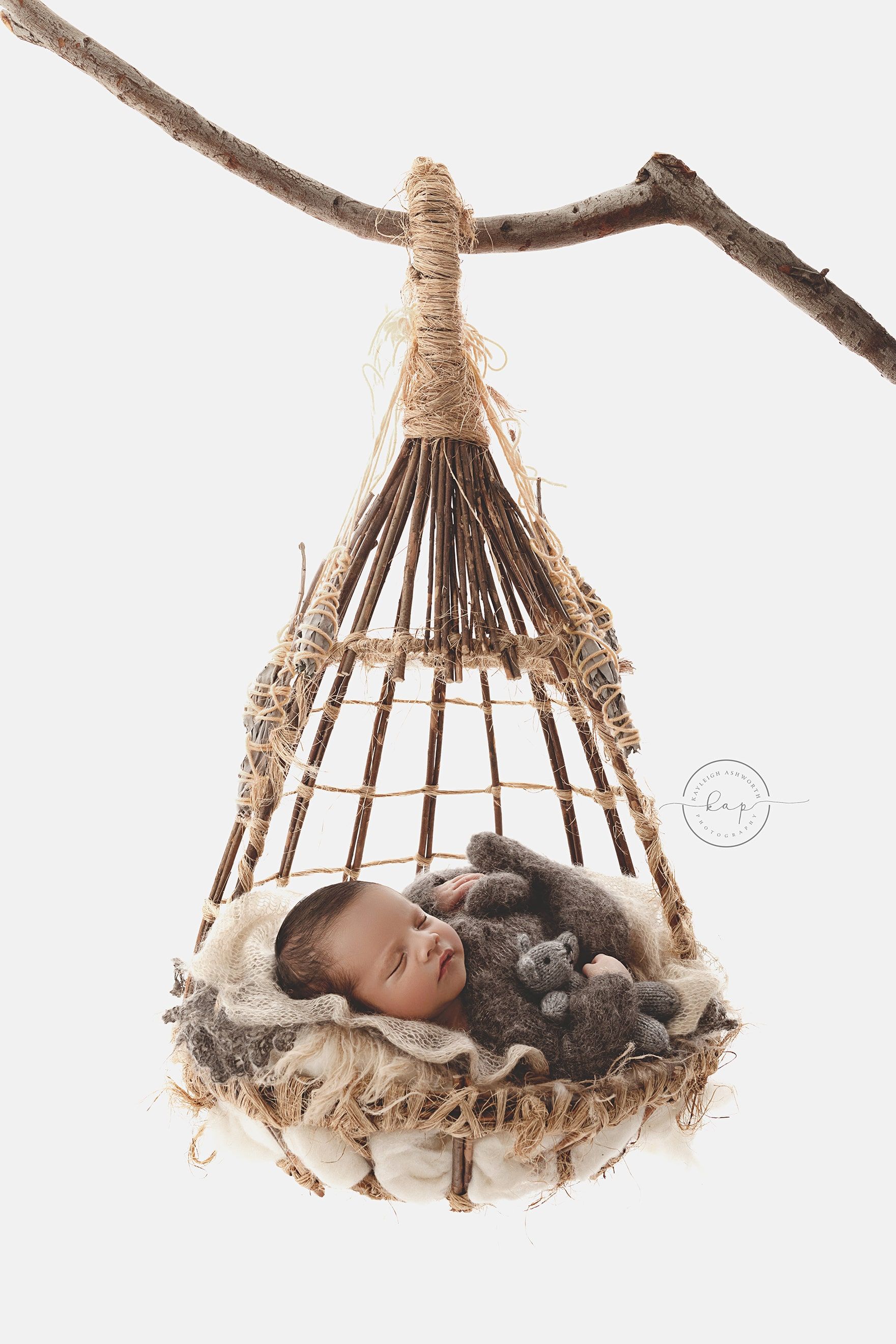 A newborn baby is sleeping in a hammock hanging from a tree branch.