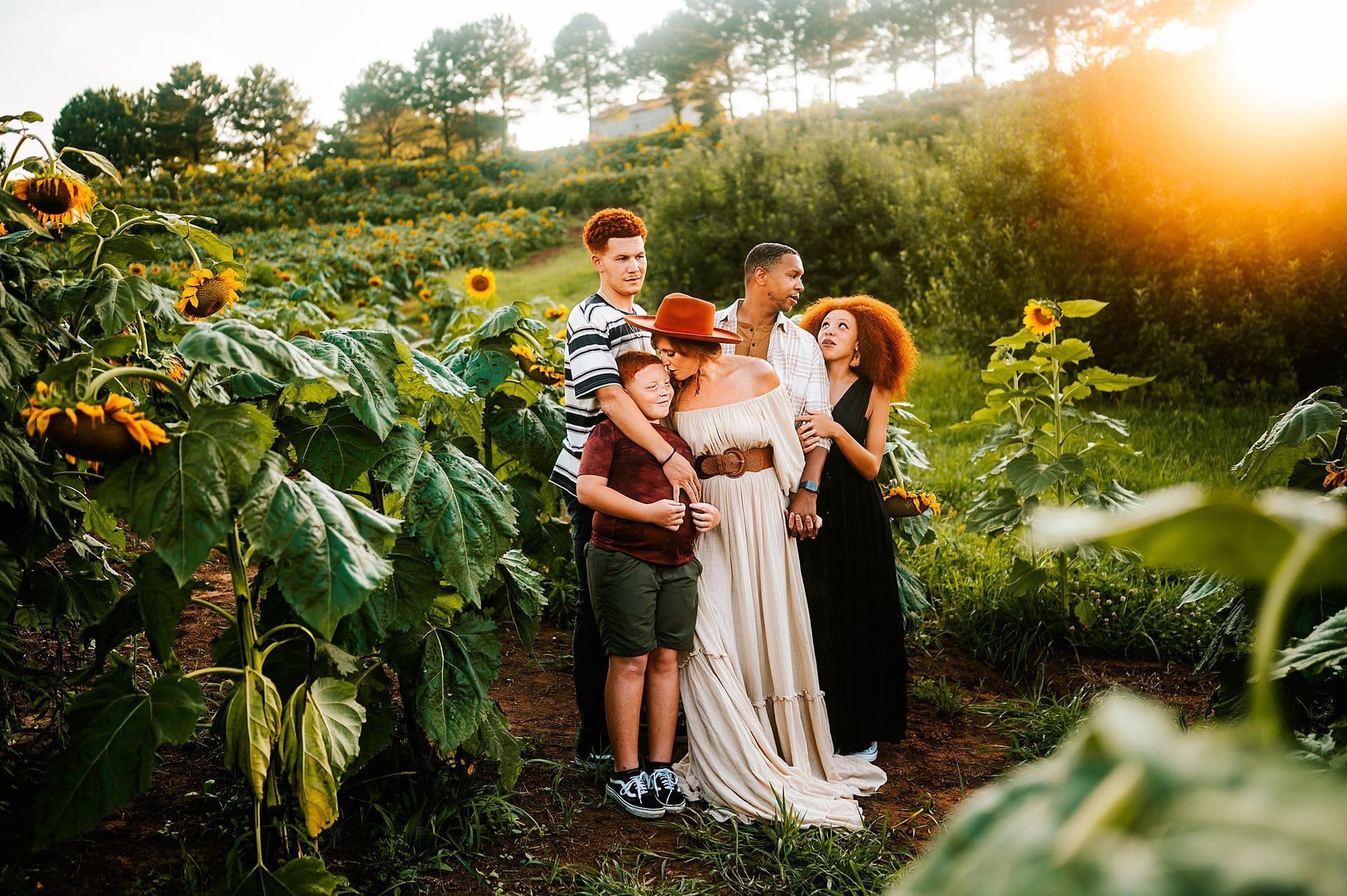 A family is standing in a field of sunflowers.