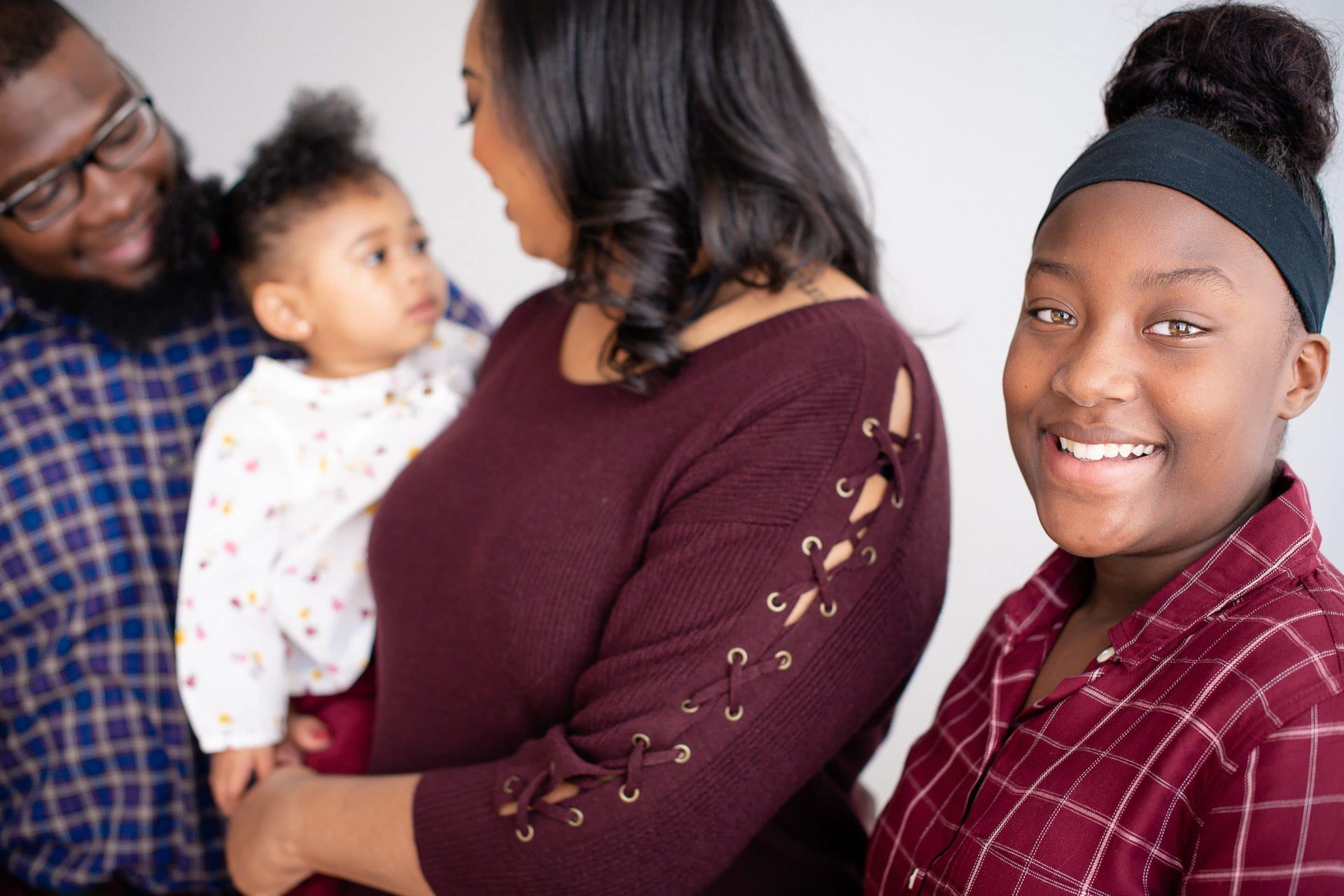 A family is posing for a picture together and the woman is holding a baby.