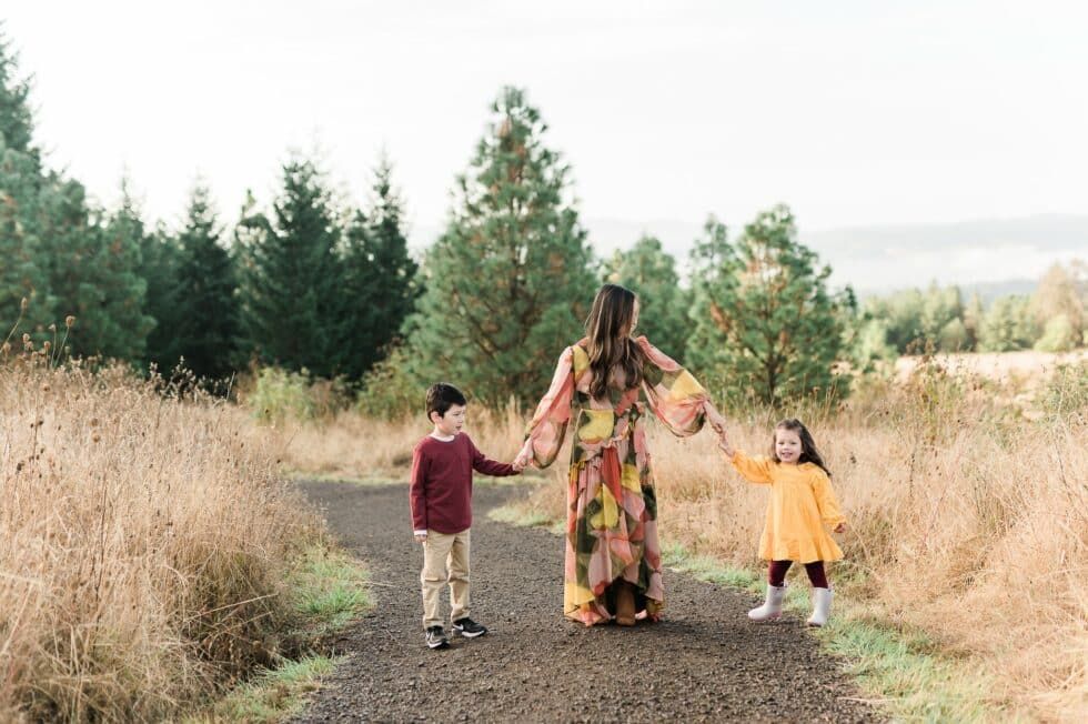 A woman and two children are walking down a path holding hands.