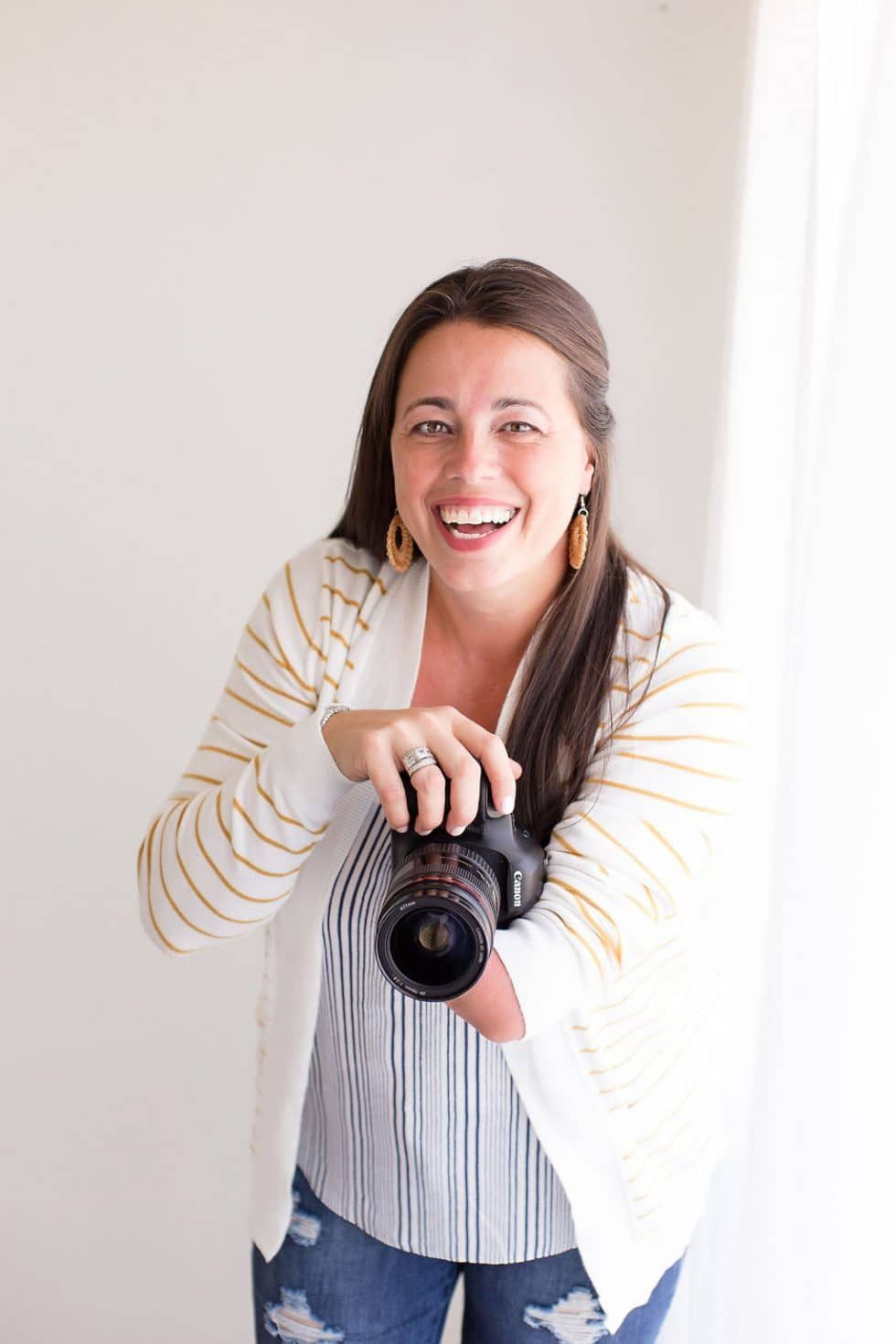 A woman is holding a camera in her hands and smiling.