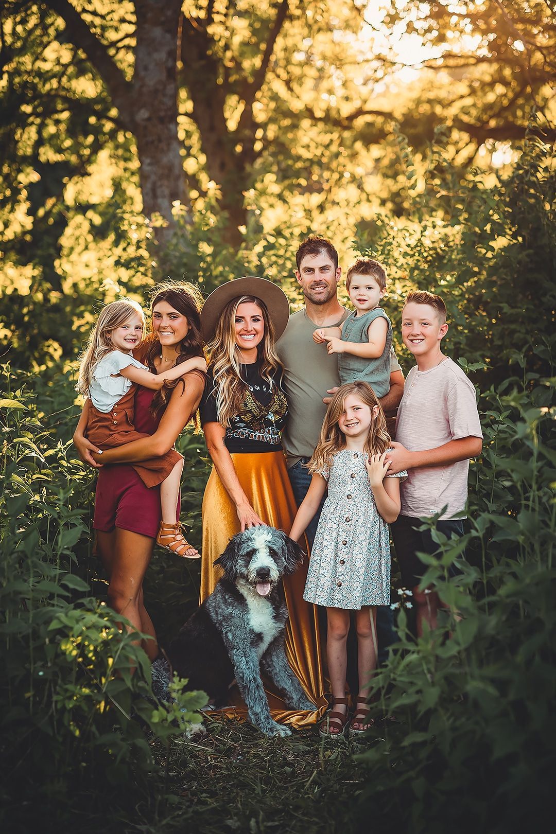 A family posing for a picture with a dog in the woods.