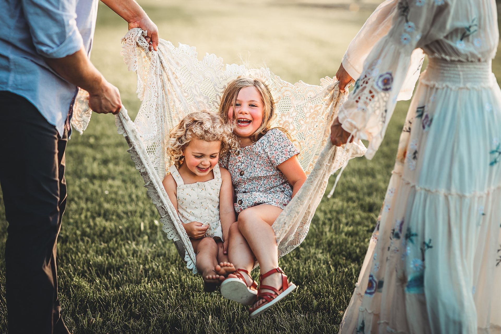 A family is sitting in a hammock in the grass.