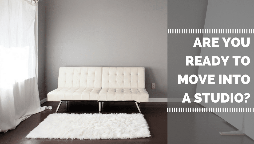 An empty living room with a white couch and a white rug.