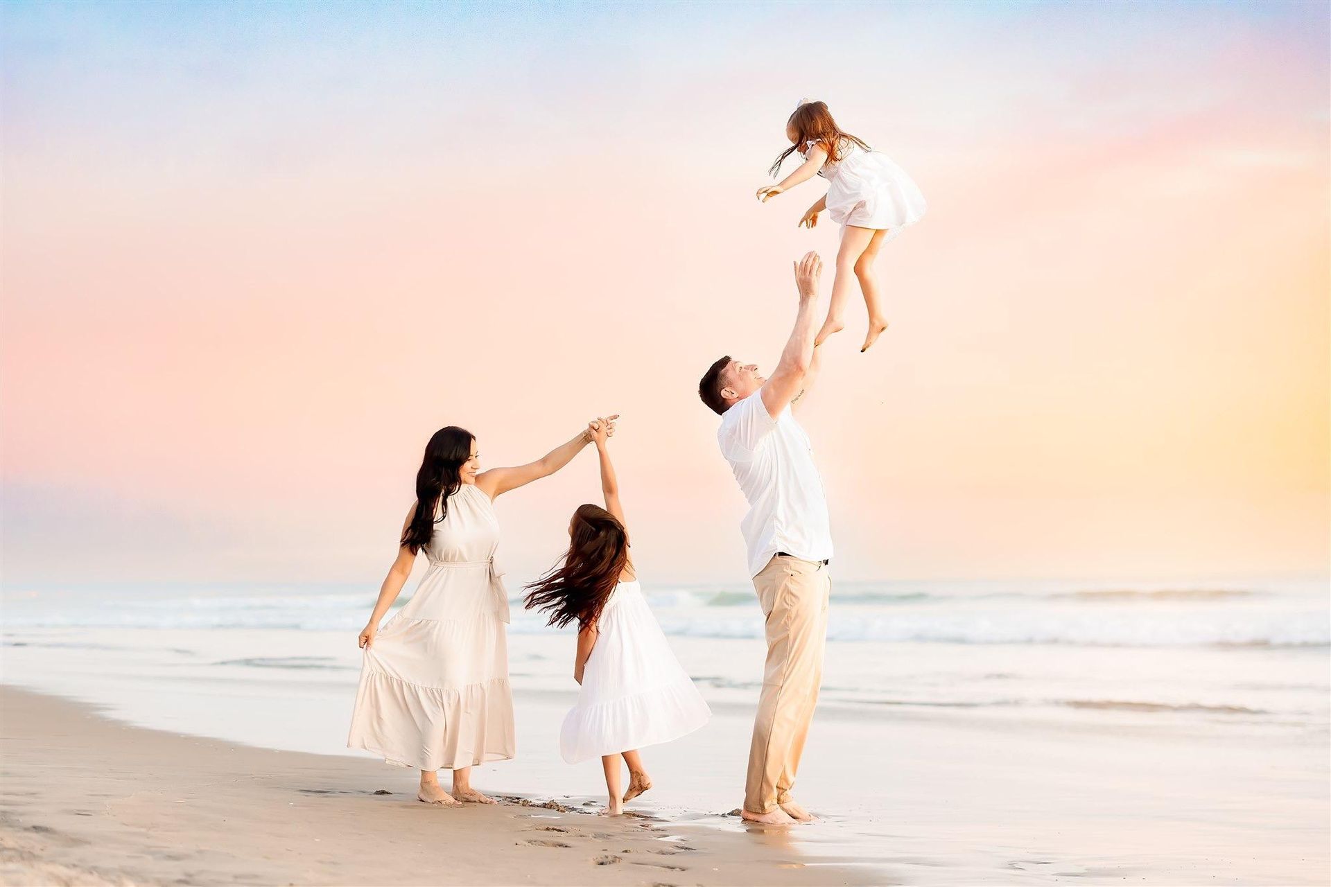 A family is playing on the beach at sunset.