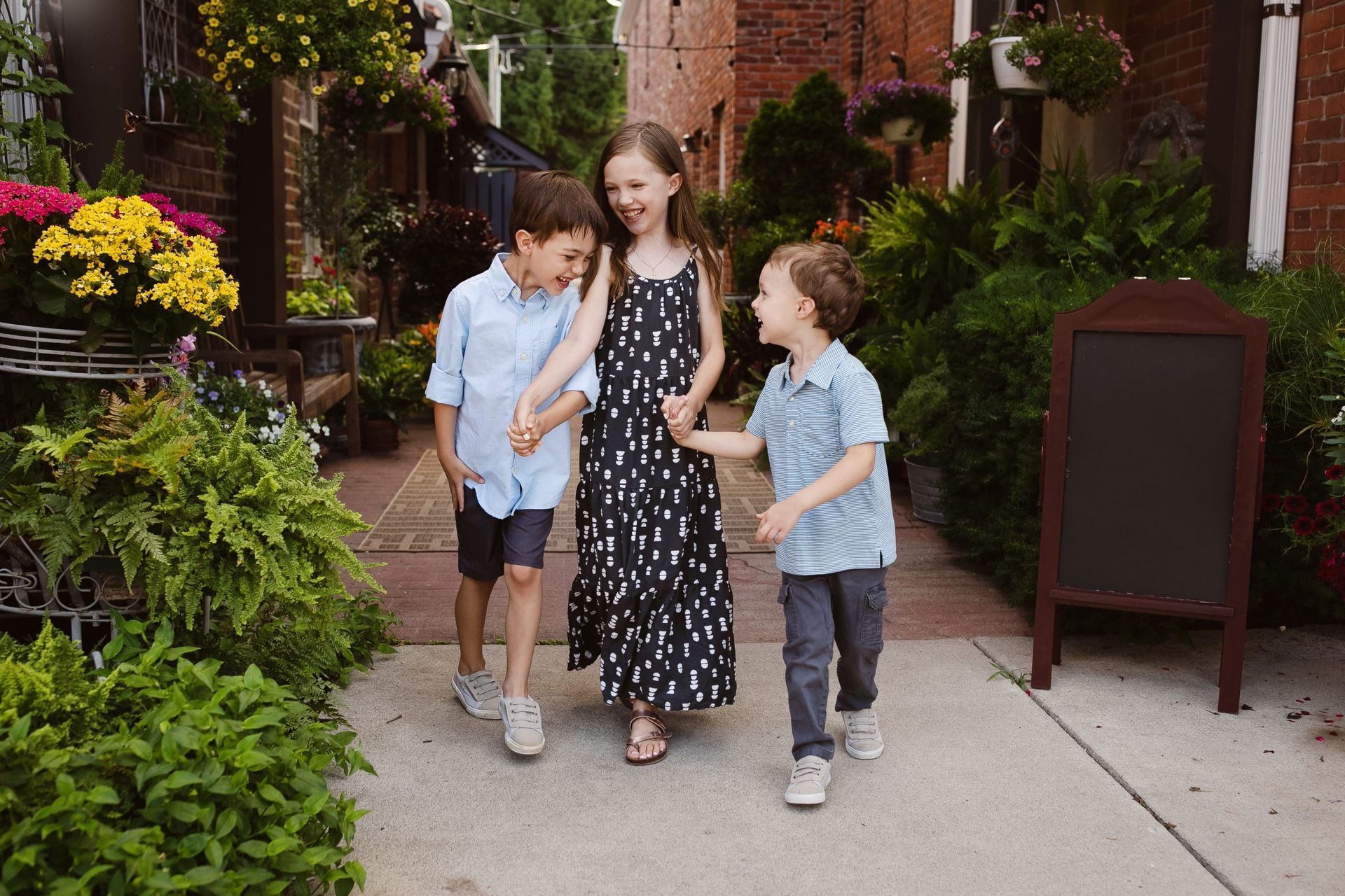 A woman and two children are walking down a sidewalk holding hands.