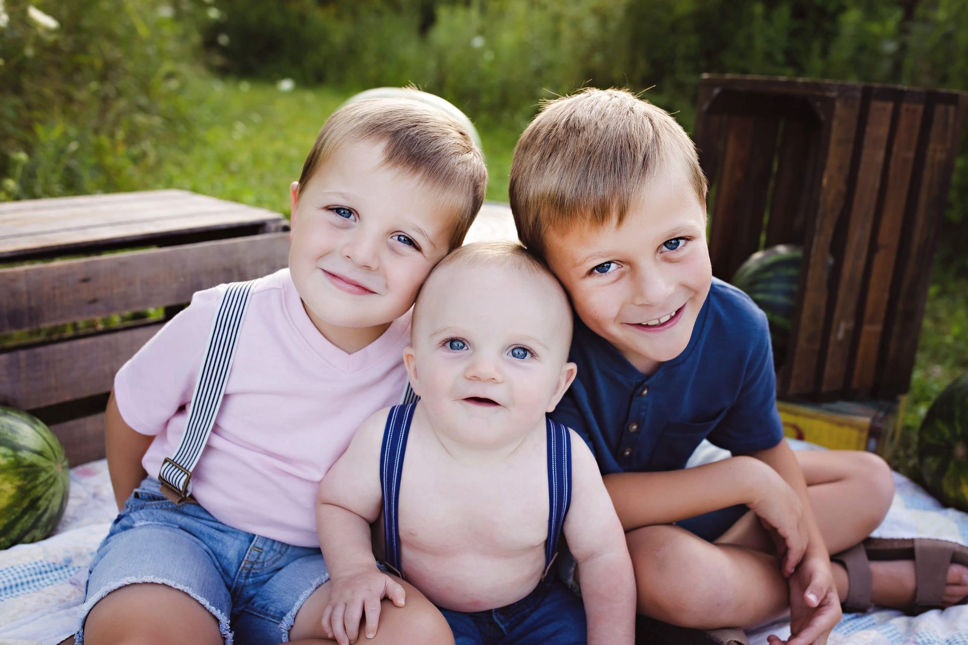 Three young boys are sitting next to each other on a blanket.