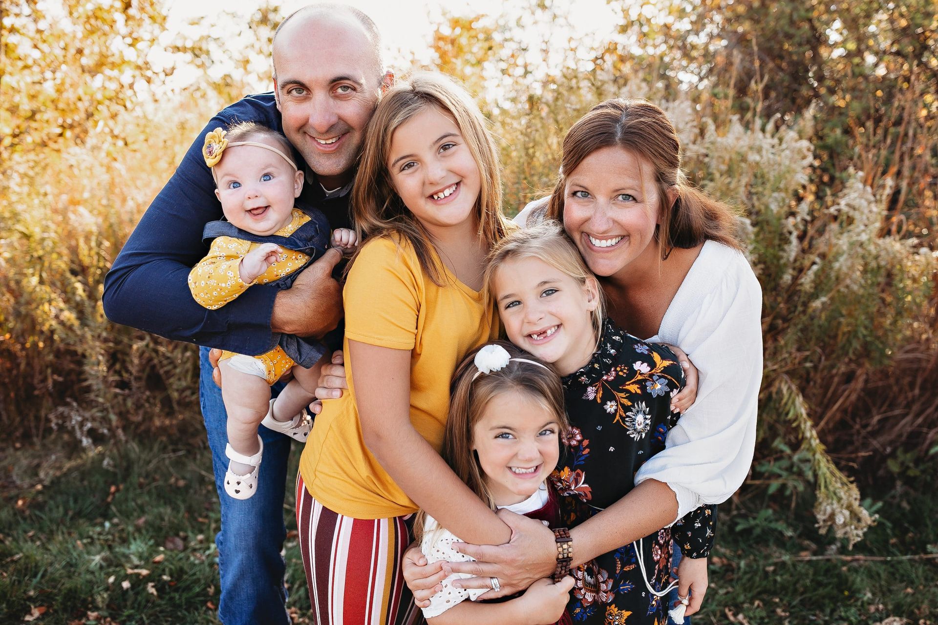 A family is posing for a picture together in a park.