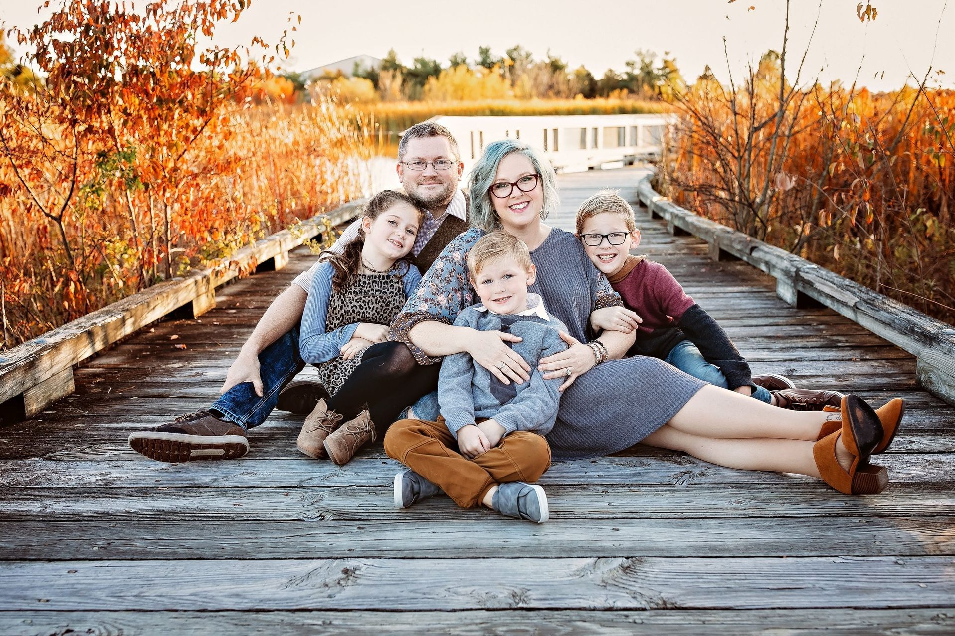 A family is posing for a picture on a wooden bridge.