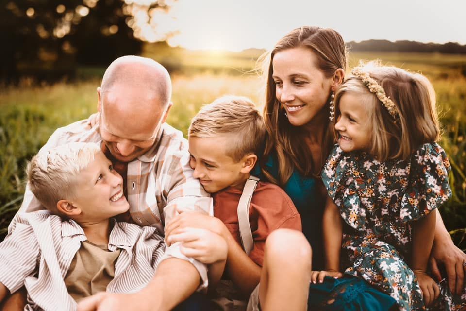 A family is sitting on the grass in a field.