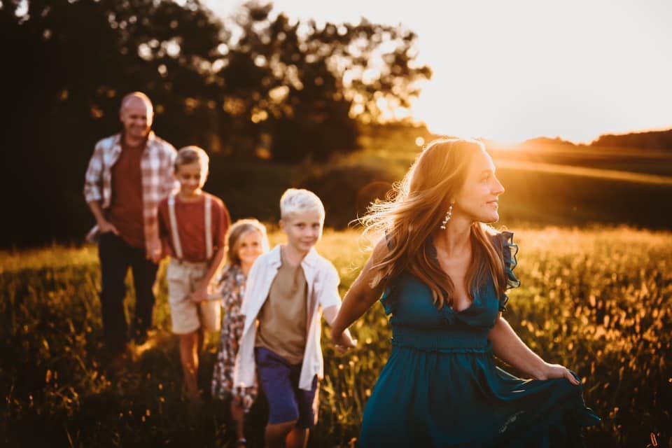 A family is walking through a field at sunset.