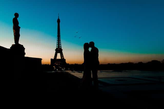 A couple kissing in front of the eiffel tower at sunset