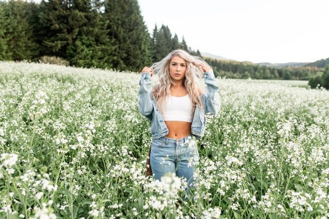 A woman is standing in a field of white flowers.