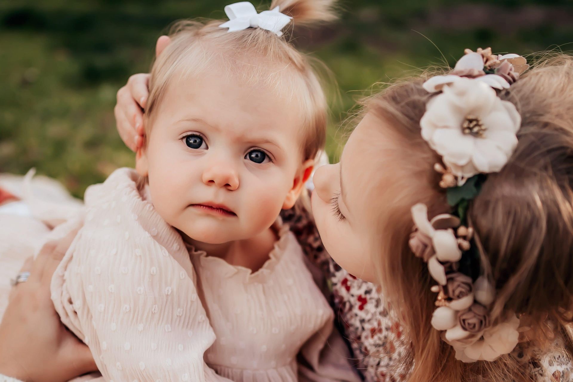 A woman is kissing a baby girl on the cheek.