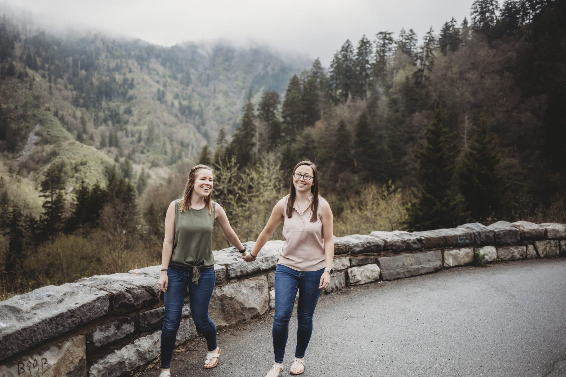 Two women are walking down a road holding hands.