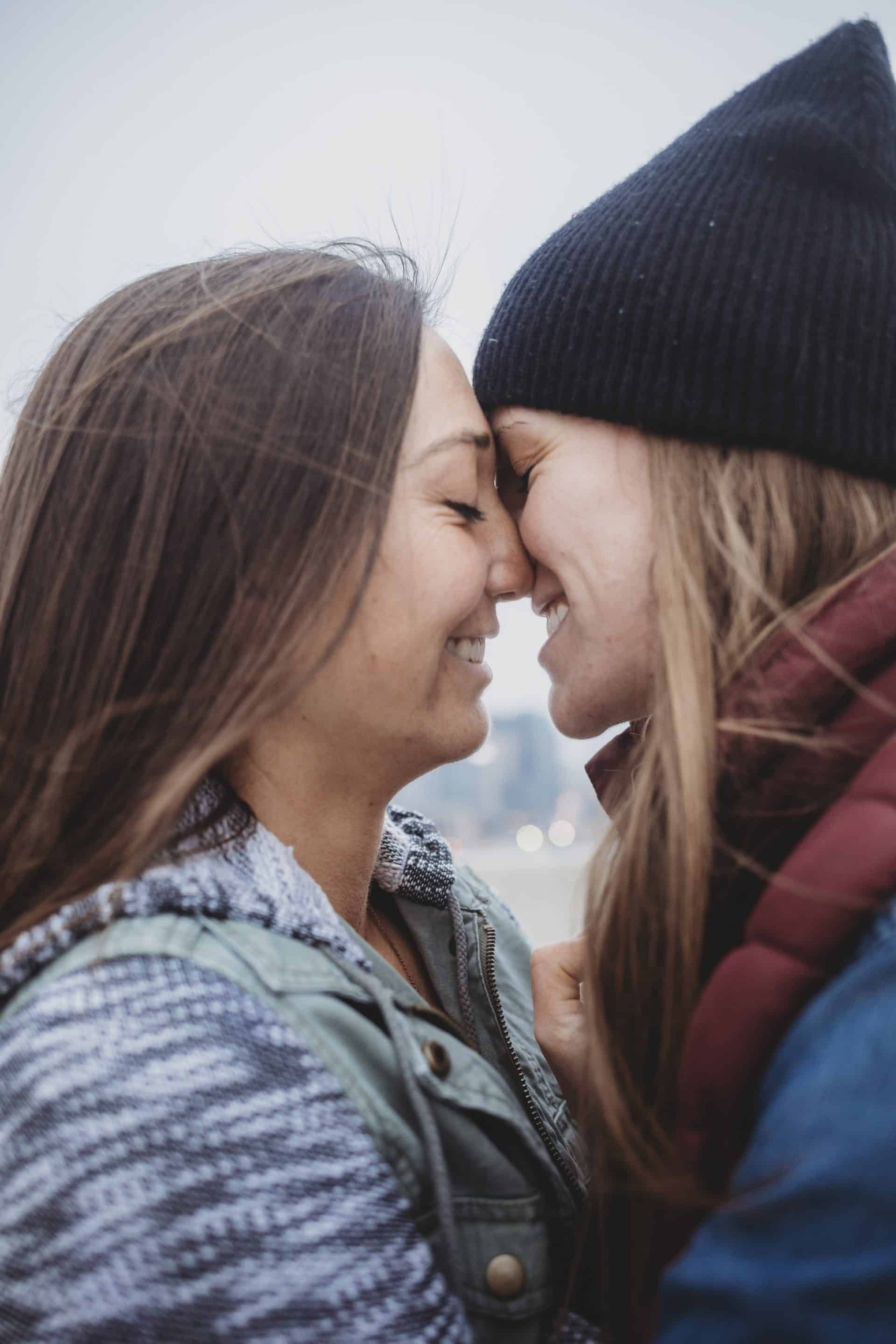 A couple of women are kissing each other on the forehead.