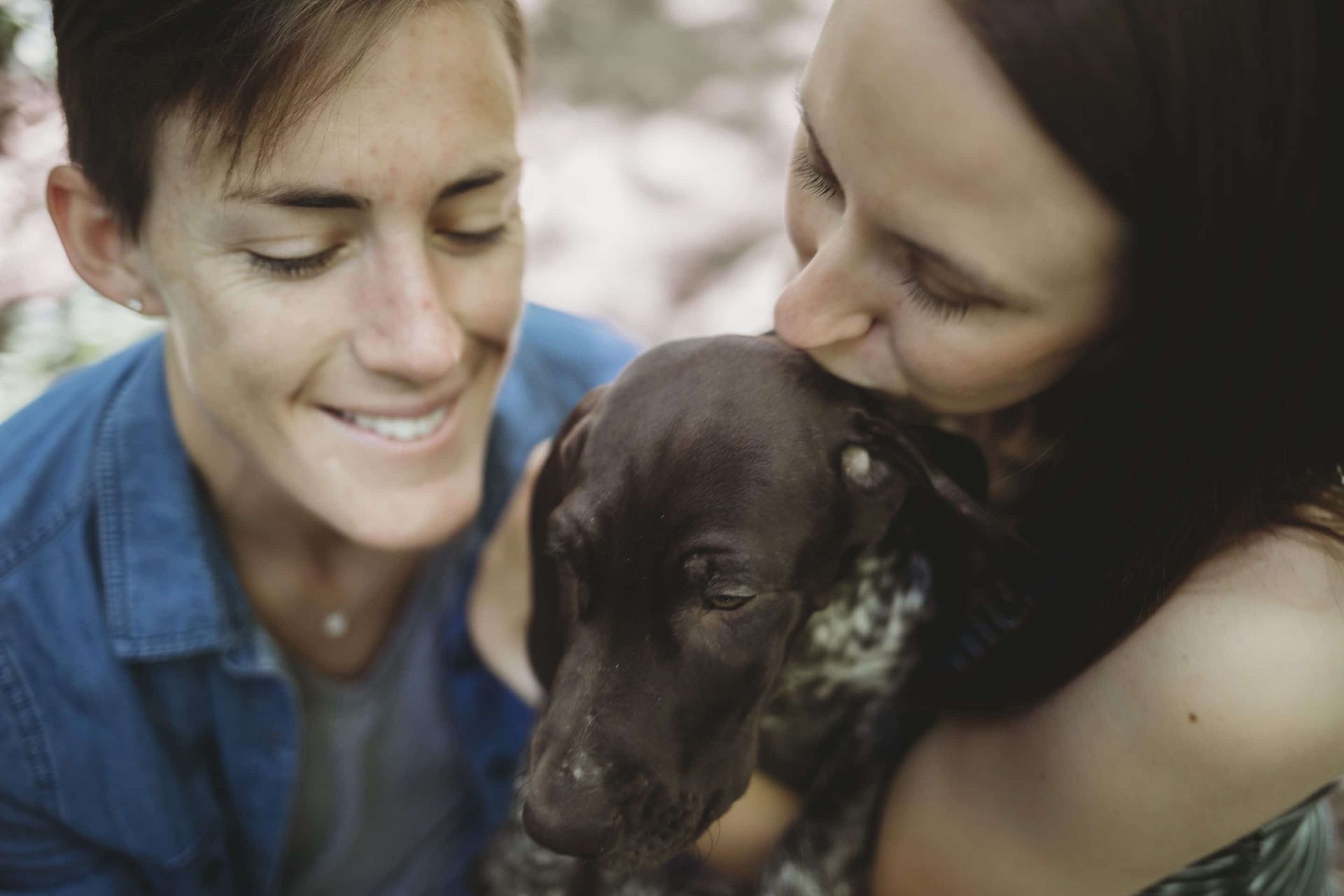 A couple of women are holding a dog in their arms.