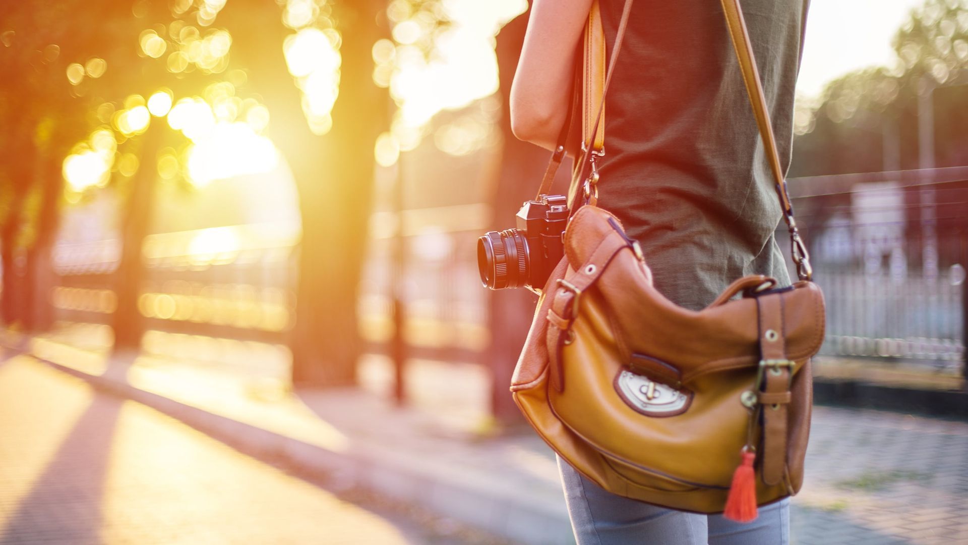 A woman is holding a camera and a purse.