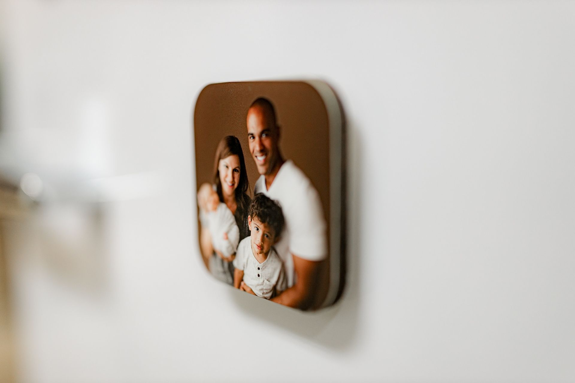 A picture of a family is hanging on a white wall.