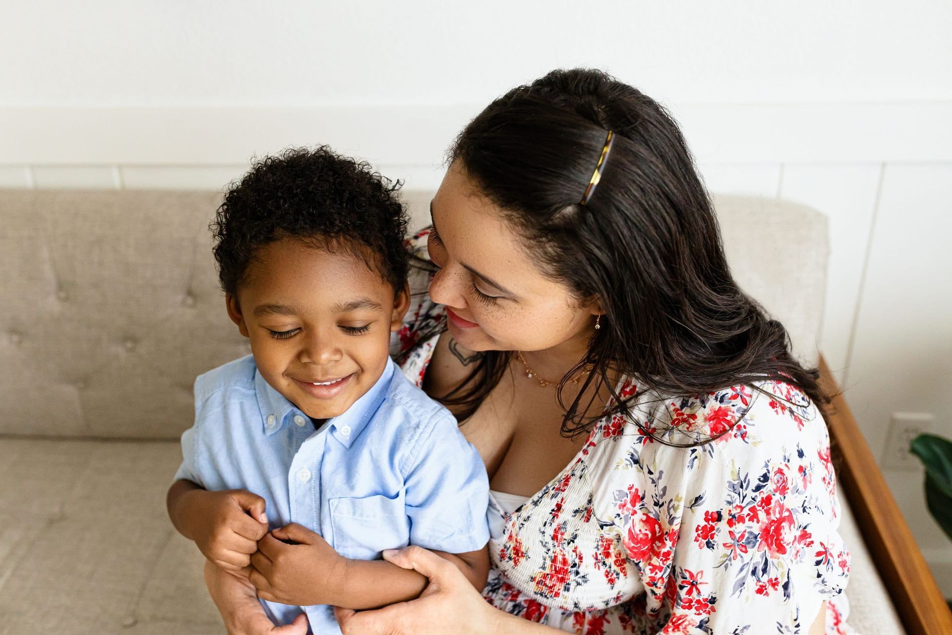 A woman is sitting on a couch holding a little boy.