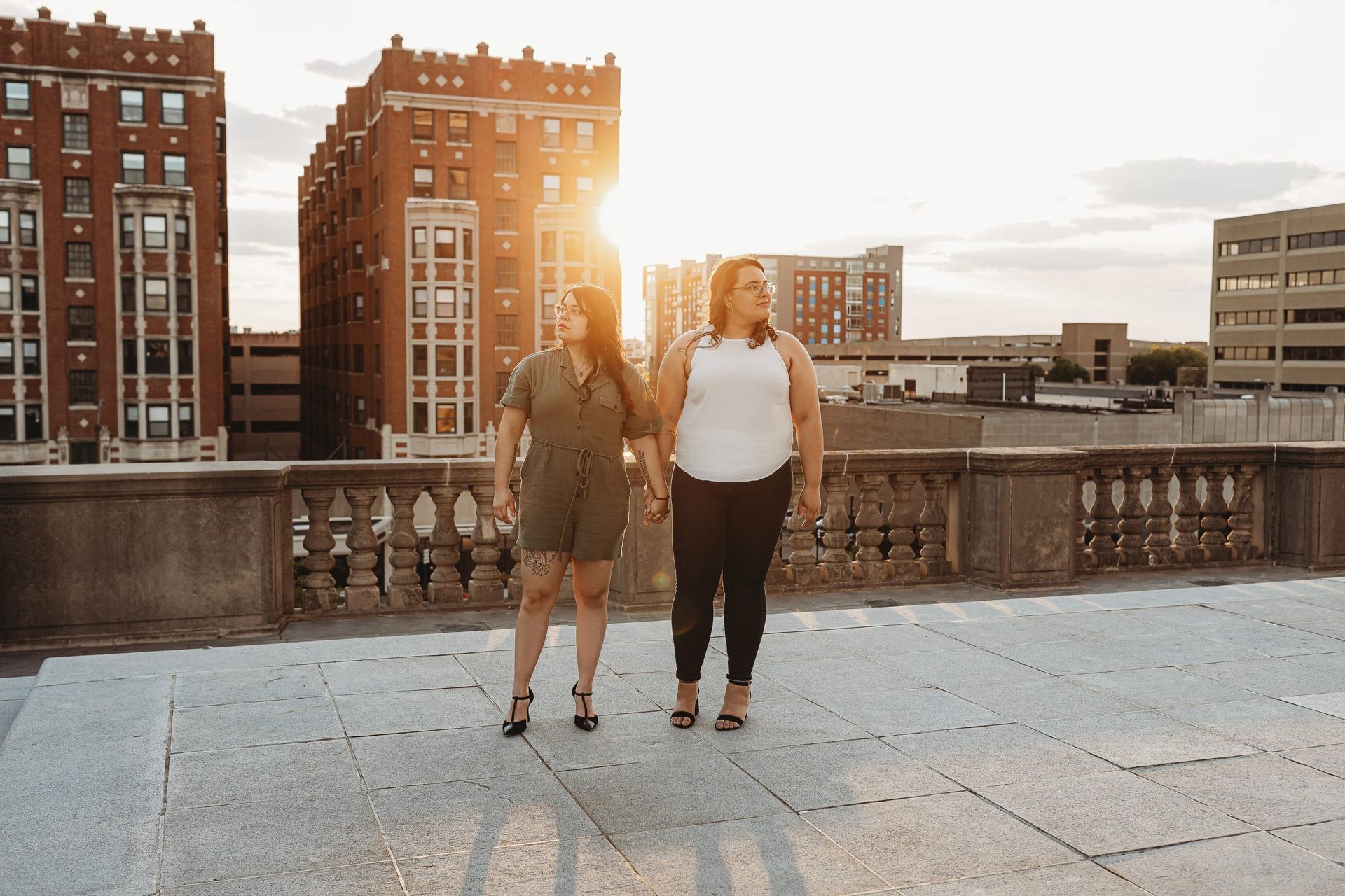 Two women are walking on a balcony holding hands.