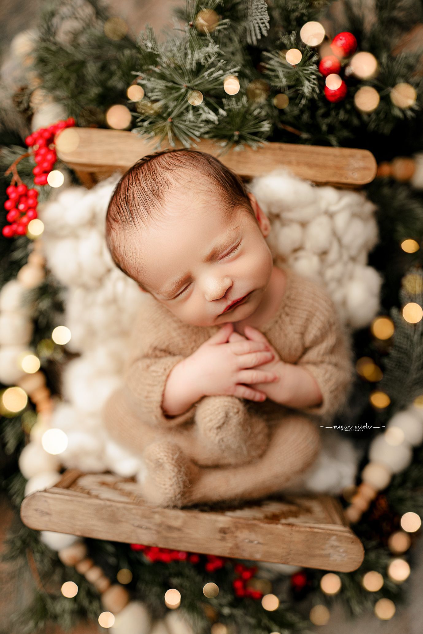 A newborn baby is sleeping in a wooden crate surrounded by christmas lights.