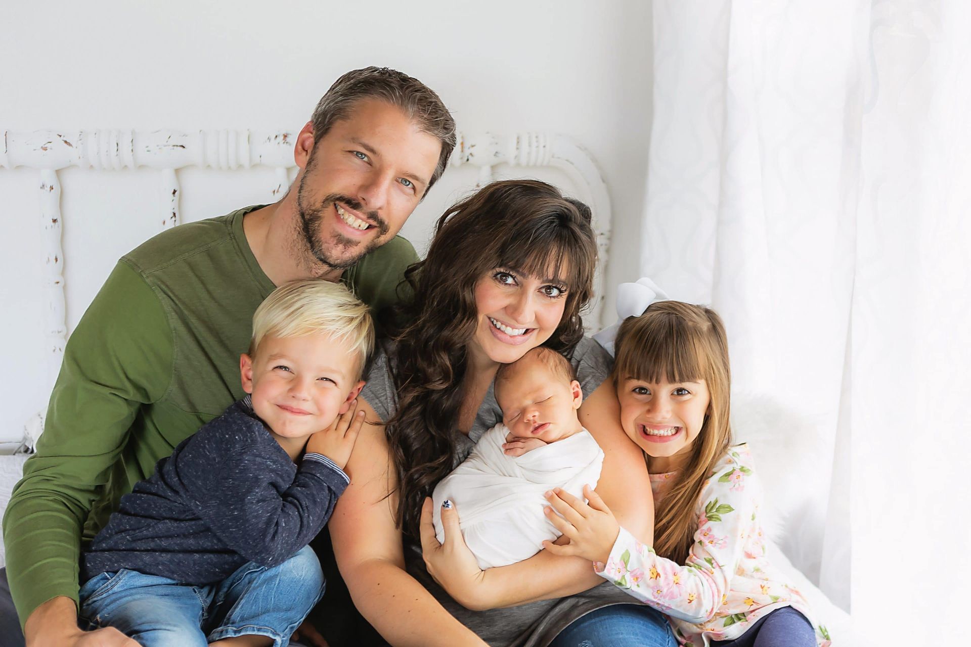 A family is posing for a picture with a newborn baby.