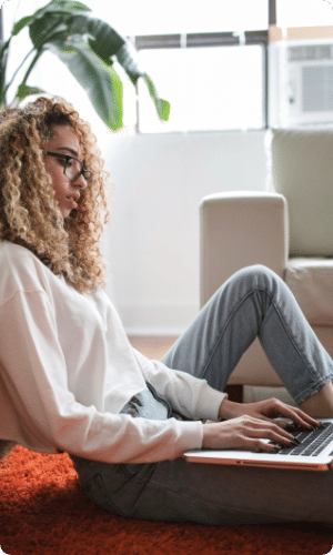 A woman is sitting on the floor using a laptop computer.