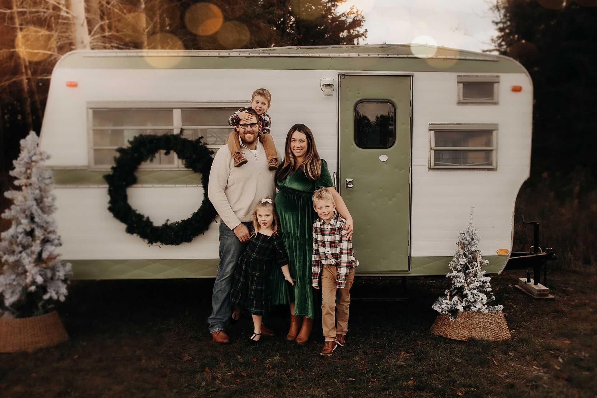 A family is standing in front of a trailer decorated for christmas.