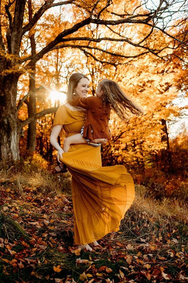 A woman in a yellow dress is holding a little girl in her arms.