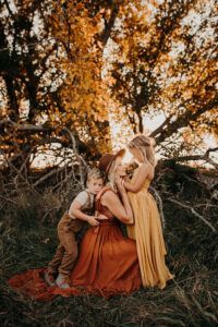 A woman and two children are posing for a picture in a field.