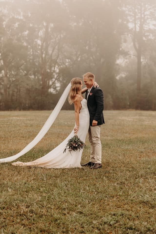 A bride and groom are posing for a picture in a foggy field.