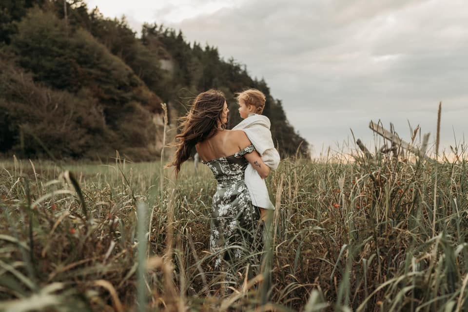 A woman is holding a child in a field.