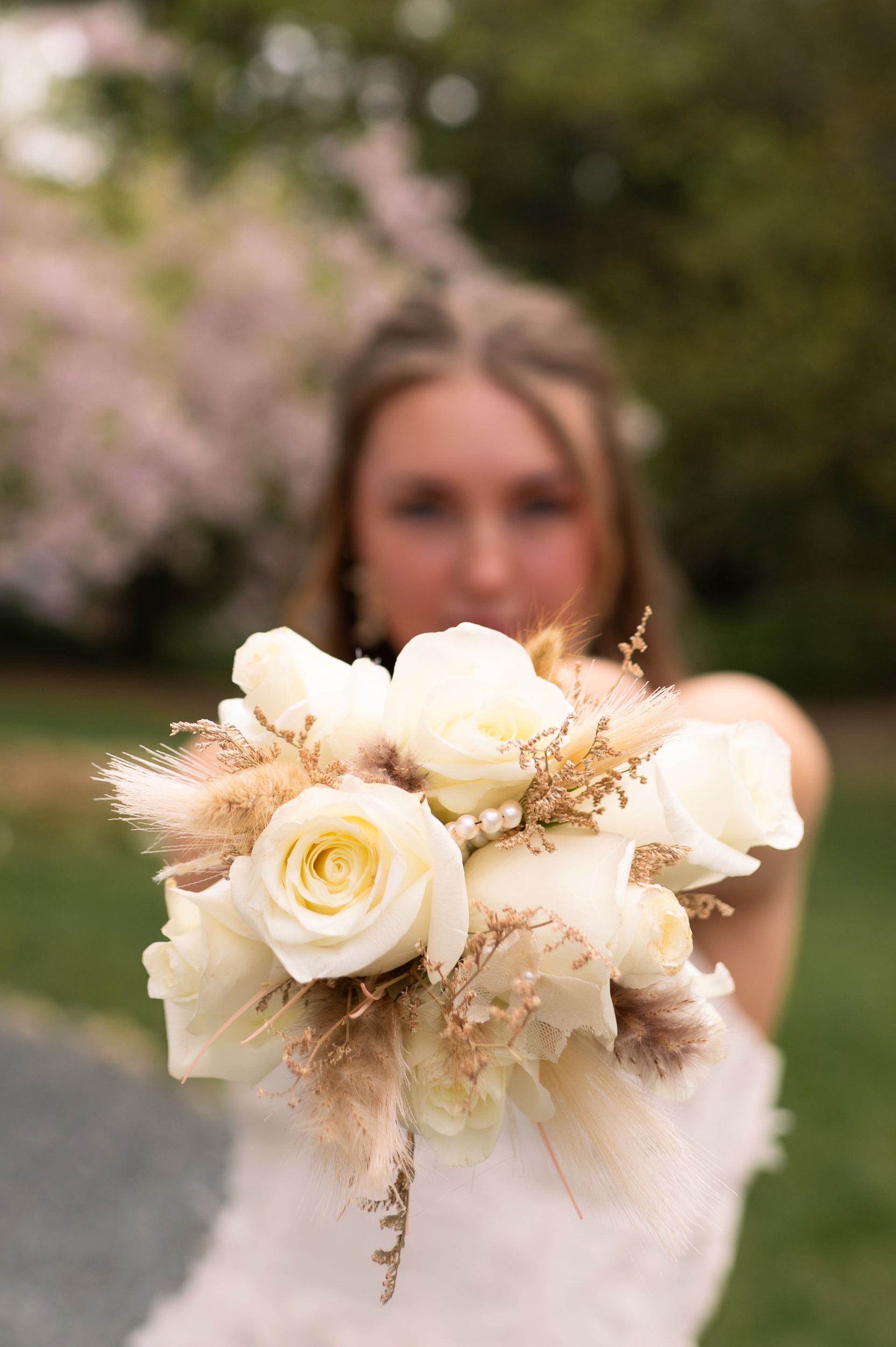 A woman in a white dress is holding a bouquet of white flowers.