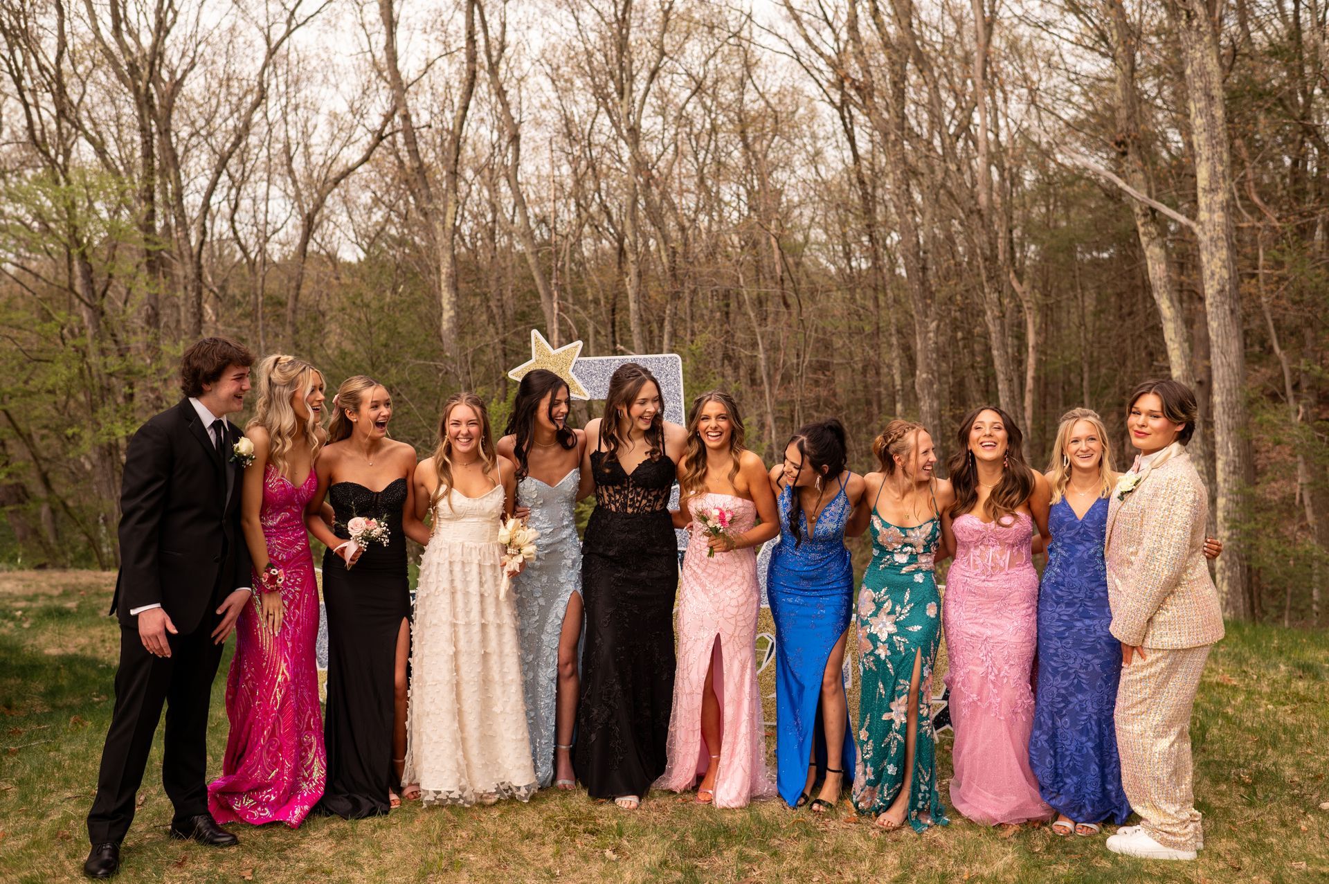 A group of people are posing for a picture in a field. prom.