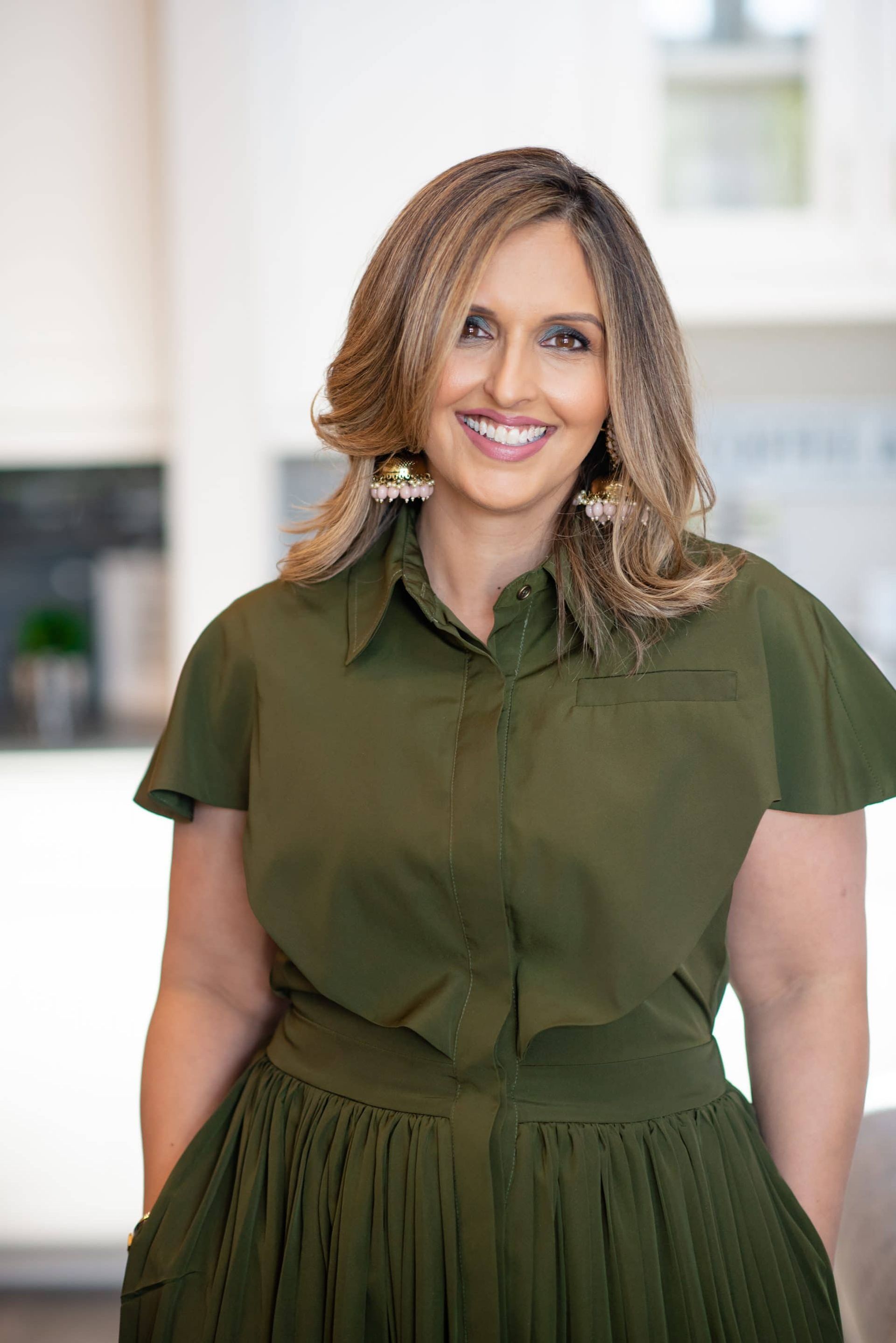 A woman in a green shirt and skirt is smiling for the camera.